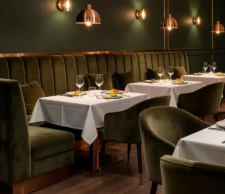 Teplý večerní interiér restaurace Vellaro s osvětlenými stoly